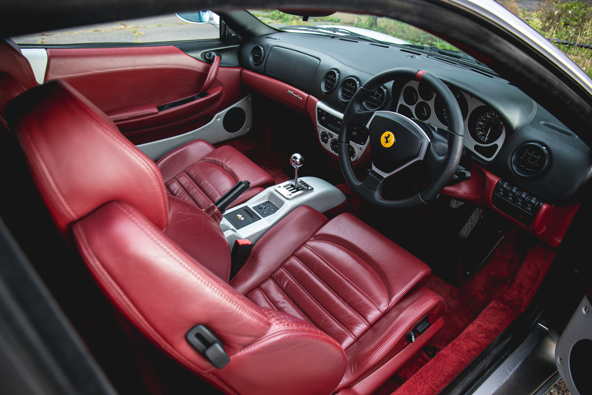 A silver Ferrari 360 Modena with a red leather interior